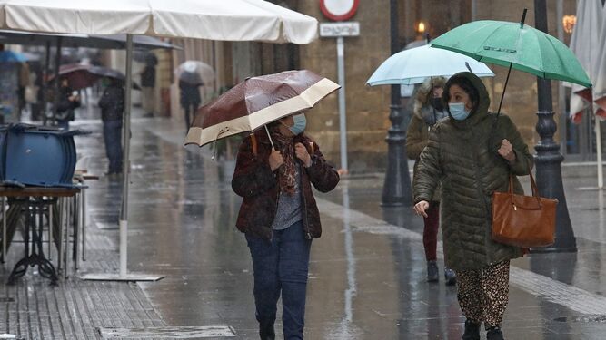 Dos mujeres con paraguas por el centro de Cádiz.