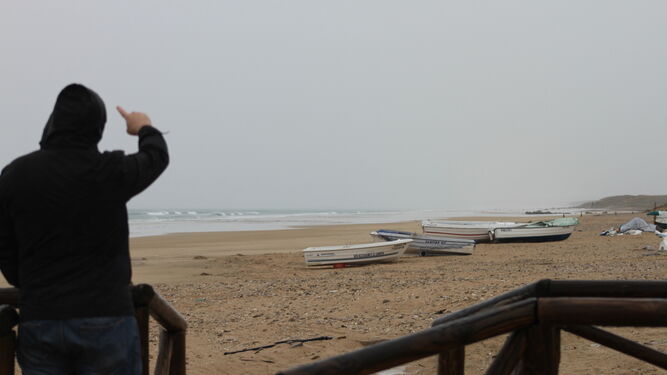 Un vecino señala desde la playa de Zahara de los Atunes en un día lluvioso donde vierte el emisario submarino.