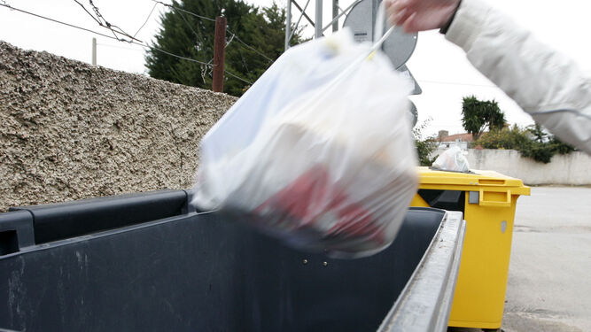 Una persona deposita una bolsa de basura en un contenedor, en una imagen de archivo.