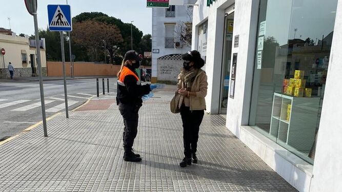 Una voluntaria de Protección Civil informa a una mujer sobre las medidas de seguridad.