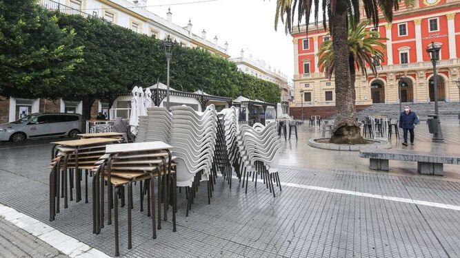Mesas y sillas recogidas de una terraza de la Plaza del Rey.