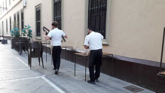 Camareros recogiendo mesas antes de la hora de cierre decretada.