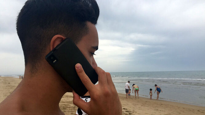 Un joven hablando por teléfono en la playa.