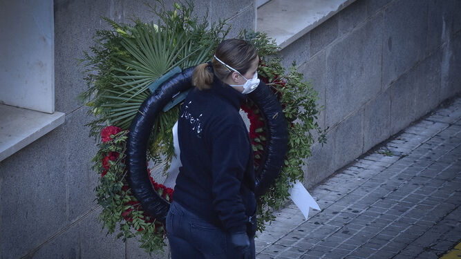 Una mujer transporta una corona de flores después de la muerte de una persona con Covid.