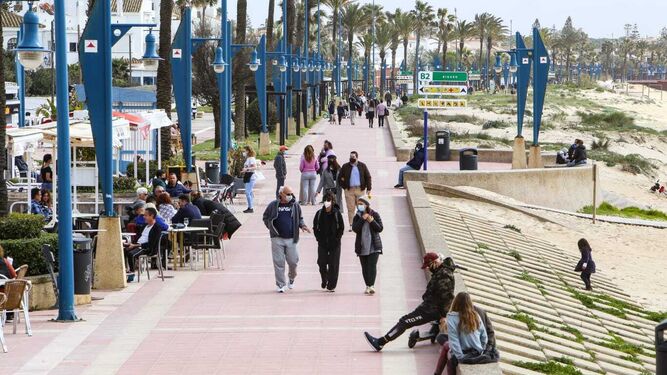 Personas con mascarillas paseando por el paseo marítimo de La Barrosa