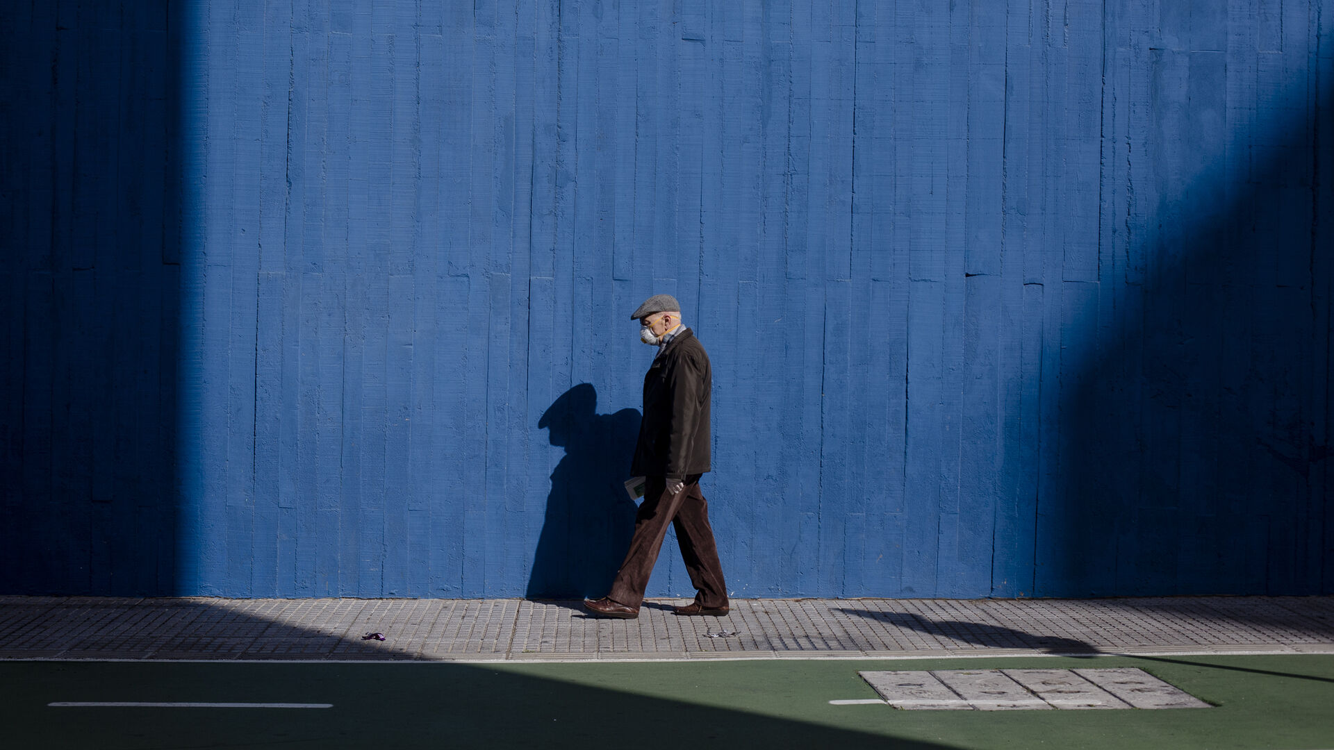 02/04/2020. 11:18 AM. Una persona mayor con guantes y mascarillas pasea por la calle durante  las horas permitidas.