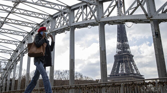 Una mujer pasea cerca de la Torre Eiffel.