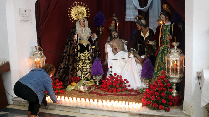 Una mujer coloca una vela a los pies de la Virgen de los Dolores