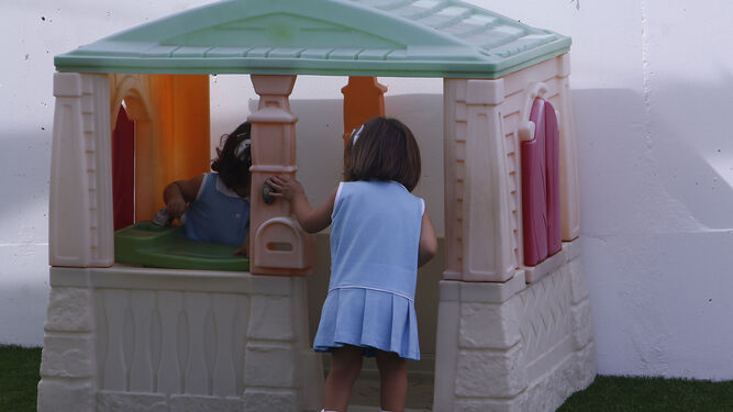Dos niñas juegan en el patio de una guardería.