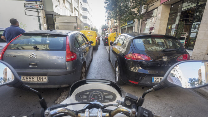Varios vehículos aparcados y circulando por la avenida de Portugal en Cádiz.