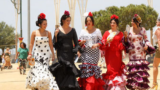Mujeres con sus trajes de flamenca por el ferial de las Albinas en junio de 2019.