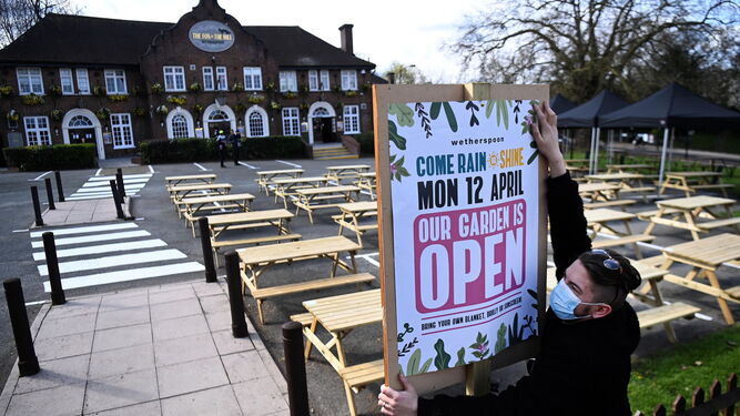 Un empleado del pub Fox on the Hill, en Londres, cuelga un cartel anunciando la reapertura.