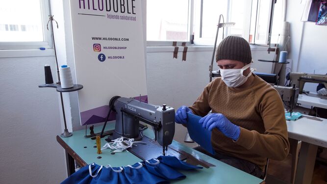 Una persona en riesgo de exclusión fabricando mascarillas, gracias a una iniciativa de la Diputación de Málaga con la colaboración de CaixaBank y Fundación Bancaria "La  Caixa".
