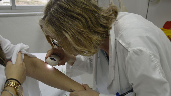 Una dermatóloga realiza una exploración  en una imagen de archivo previa a la pandemia.
