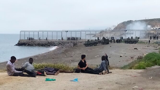 Un grupo de migrantes observa el despliegue del Ejército de Tierra.