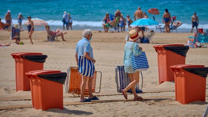 Dos personas con mascarilla llegan a una playa de Cádiz.