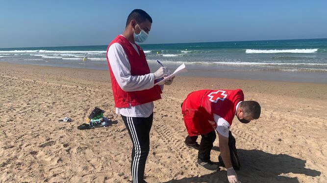 Voluntarios de Cruz Roja recogen residuos en la playa.