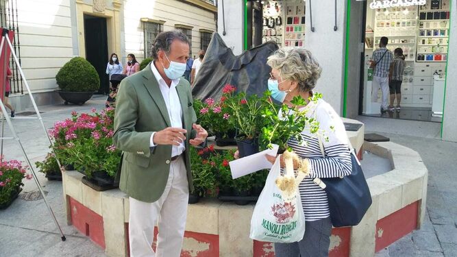 El alcalde, José María Román, entrega macetas de gitanillas a una ciudadana.