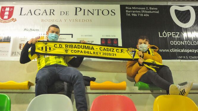 Dos aficionados sostienen una bufanda conmemorativa del Ribadumia-Cádiz, de Copa.