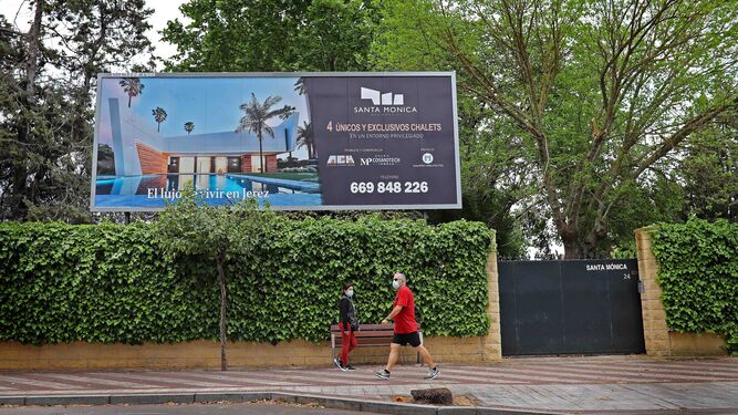 Ciudadanos pasan junto al cartel de una promoción de viviendas nuevas en Jerez.