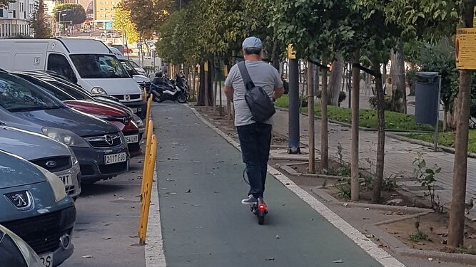 Un señor maneja un patinete, por el carril bici de la calle Arenal.