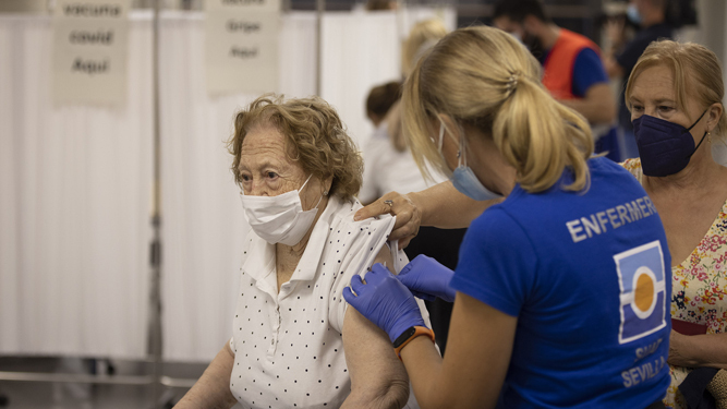 Una anciana recibe simultáneamente en Sevilla la vacuna contra la gripe y la tercera dosis de la vacuna contra el Covid-19.