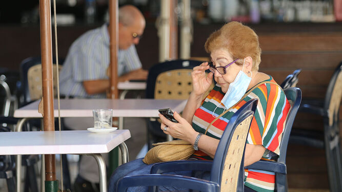 Una mujer mira el móvil con la mascarilla quitada