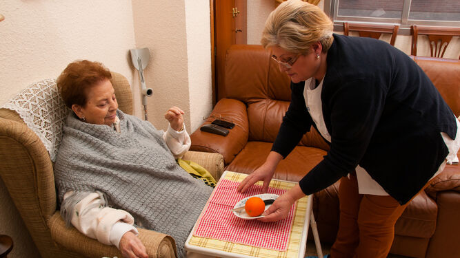 Una trabajadora de ayuda a domicilio con una persona mayor.