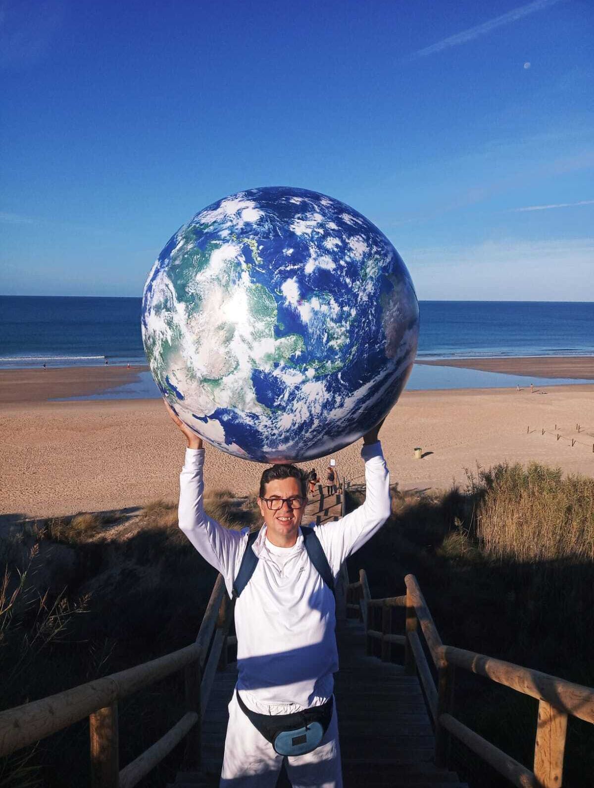 El científico chiclanero sostiene una gran bola que simboliza al planeta en una actividad celebrada en la playa de La Barrosa.