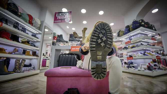Una chica se calza una bota en una tienda de zapatos del centro de Cádiz.