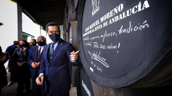 El presidente de la Junta, Juanma Moreno, mostrando su felicitación a Bodegas Barbadillo en una bota de vino.
