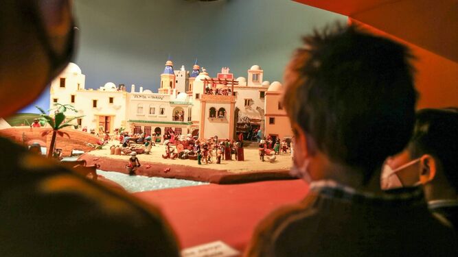 Varios niños contemplan el belén de la hermandad de la Soledad, realizado con figuras de Playmobil.