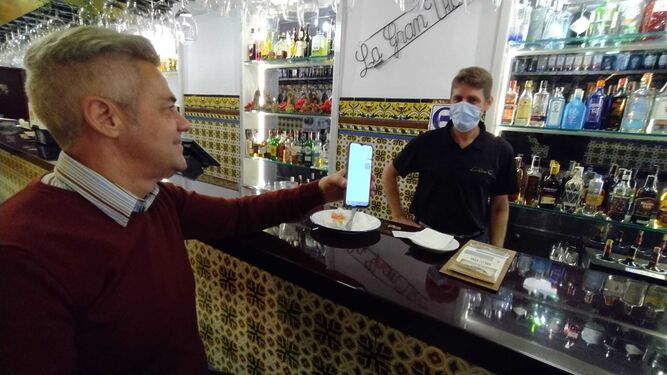 Un cliente muestra su pasaporte covid a un camarero en un bar del centro de San Fernando.