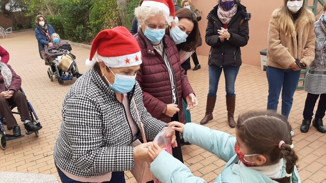 Un alumno del CEIP Camposoto entrega las felicitaciones navideñas a los usuarios del centro de Alzheimer.