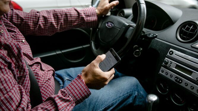 Un conductor mira los mensajes de su teléfono móvil.
