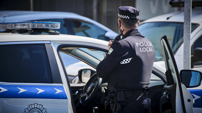 Un agente de la Policía Local de Cádiz junto a su vehículo patrulla.