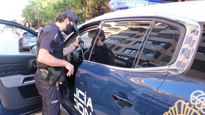 Un agente de la Policía Nacional junto a un coche patrulla