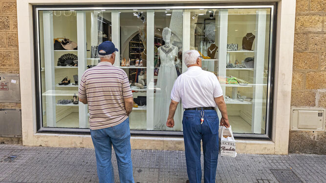 Dos hombres miran el escaparate de un comercio en Cádiz.
