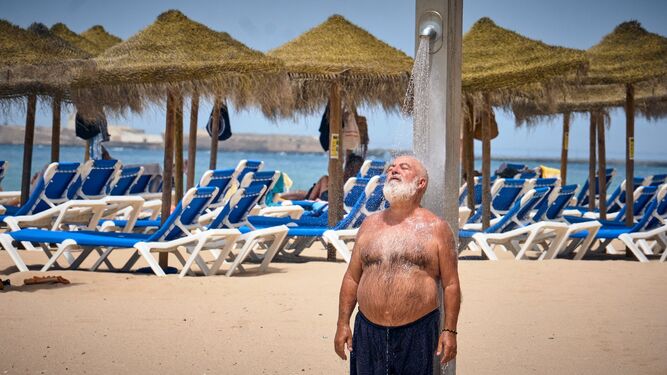 Un hombre se refresca en una de las duchas de la playa en Cádiz.