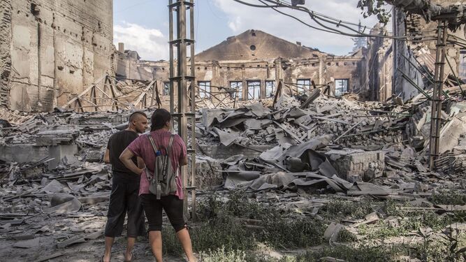 Dos civiles observan los restos de un edificio