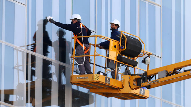 Dos operarios trabajan en la fachada de un edificio en Huelva.