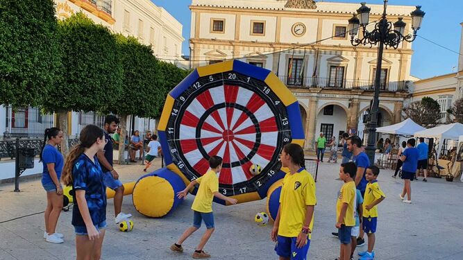 Jóvenes y pequeños prueban suerte con la diana del Cádiz en la Plaza de España de Medina.