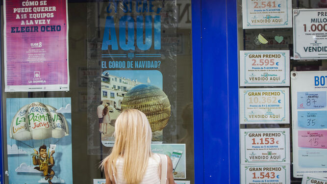 Una mujer ante un cartel publicitario del Sorteo de Navidad en una administración de loterías de Cádiz.