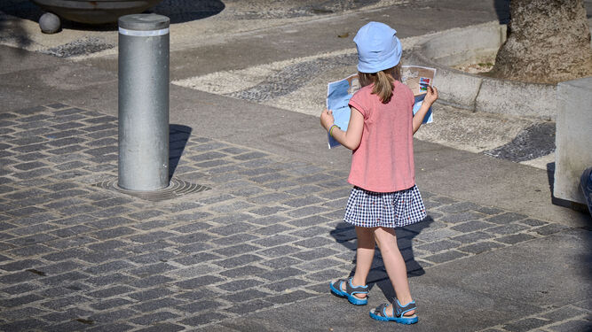 Una joven turista pasea por las calles de Cádiz plano en mano de la ciudad.