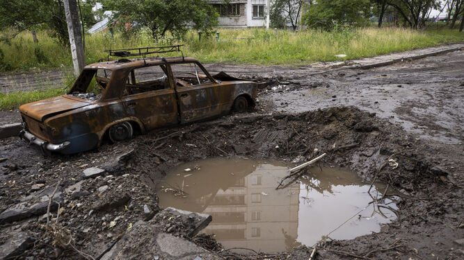Un automóvil destruido junto al cráter dejado por una explosión en en Járkov (Ucrania).