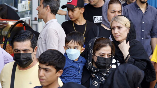 Una mujer ajusta su pañuelo sobre su cabeza mientras camina por una calle de Teherán.