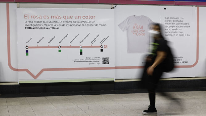 Una mujer pasa ante un cartel relativo al cáncer de mama en una estación del metro madrileño.