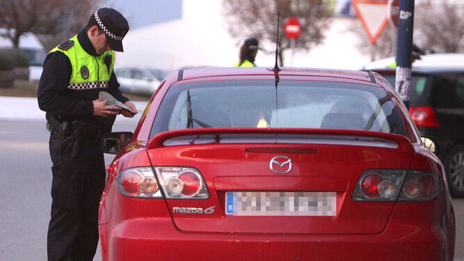 Un agente de la Policía Local multa a un  vehículo