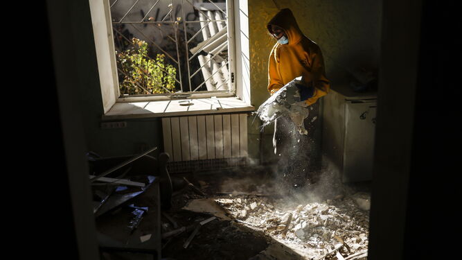 Una joven retira escombros de su dormitorio en su piso de Mykolaiv.