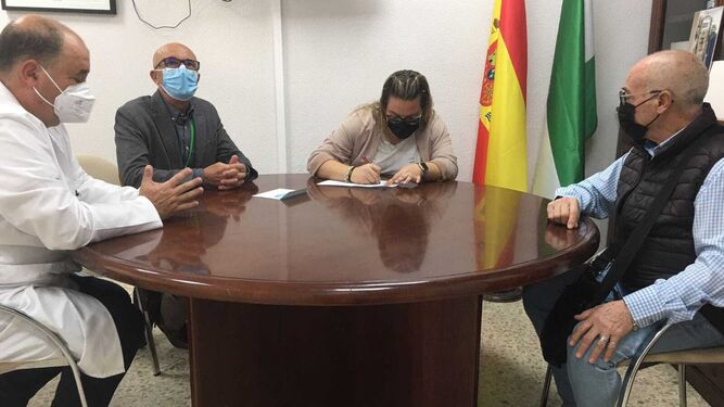 Representantes de El Rocío de Cádiz firman la donación de los televisores ante el gerente del hospital Puerta del Mar, Sebastián Quintero.